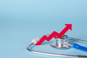 Prices are rising. Arrow diagram grows up near a stethoscope. Copy space for text.