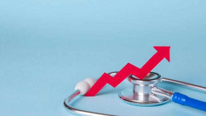 Prices are rising. Arrow diagram grows up near a stethoscope. Copy space for text.
