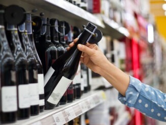 NEWS: UK Alcohol Deaths Fall for First Time Since Pandemic Woman is buying a bottle of wine at the supermarket background