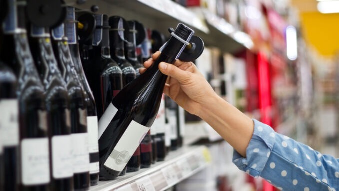 Woman is buying a bottle of wine at the supermarket background