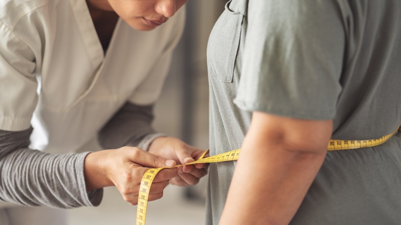 Nutritionist measures overweight woman's body with tape measure
